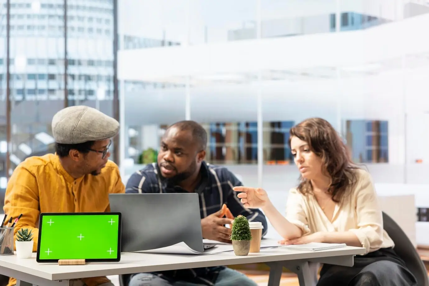 Бизнес-партнёры ведут переговоры с женщиной-риэлтором рядом с макетом.